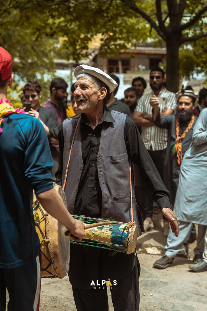 An old man playing a small drum at the chilam joshi festival